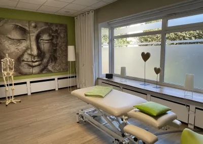 Großer Behandlungsraum mit Behandlungsliege, Fensterfront und Skelettmodell